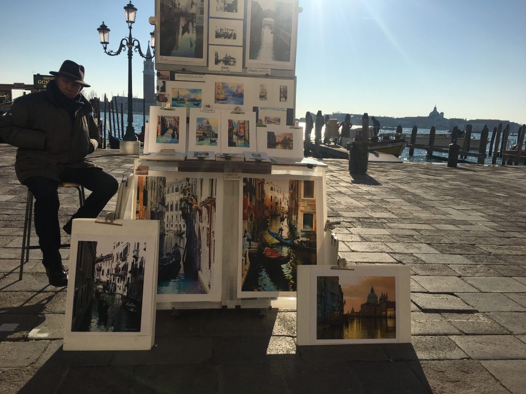 a man is selling souvenirs on the river banks of Venice