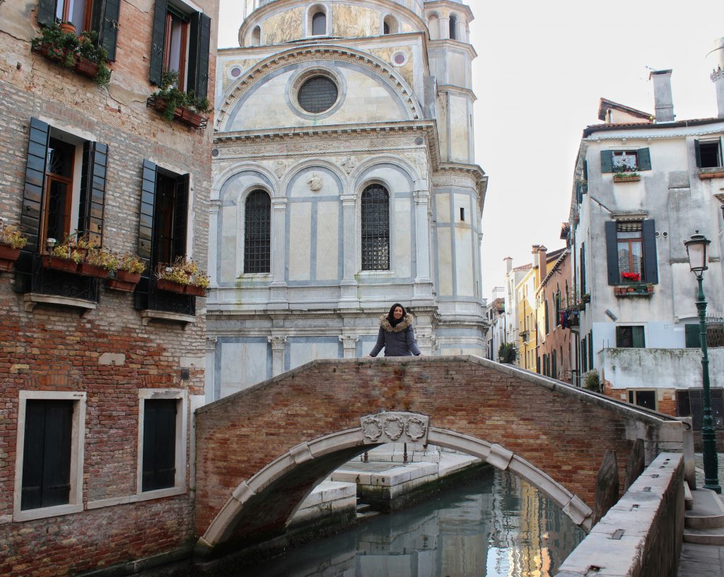 a girl is standing in the middle of a bridge in Venice