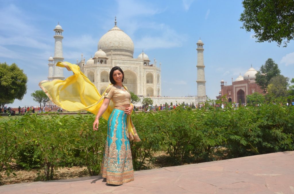 a girl in saree is posign in front of the Taj Mahal