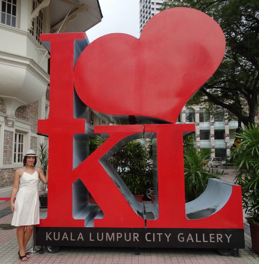 a girl is standing next to a big sign I love KL