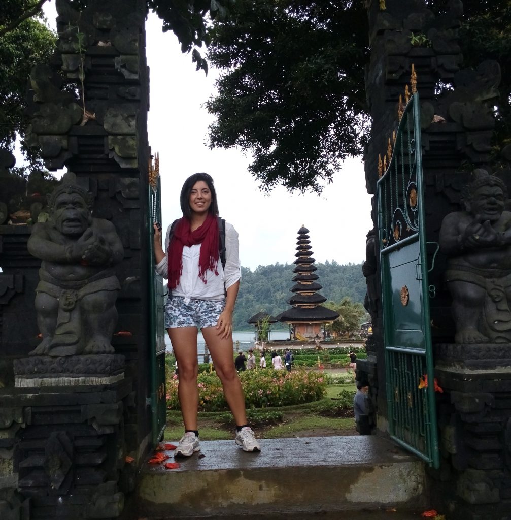 a girl is standing in front of Pur Ulun Dalu Temple in Bali