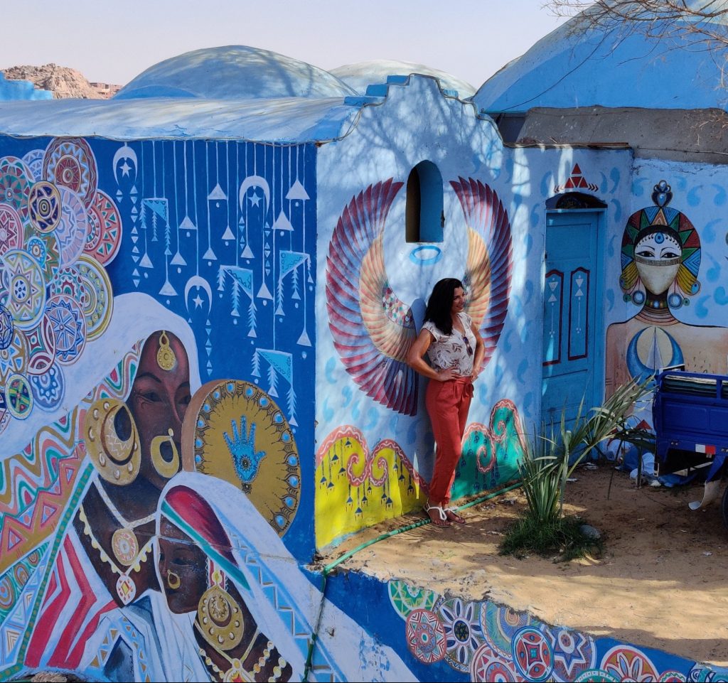 a girl is standing next to a decorated house in the Nubian Village - Aswan