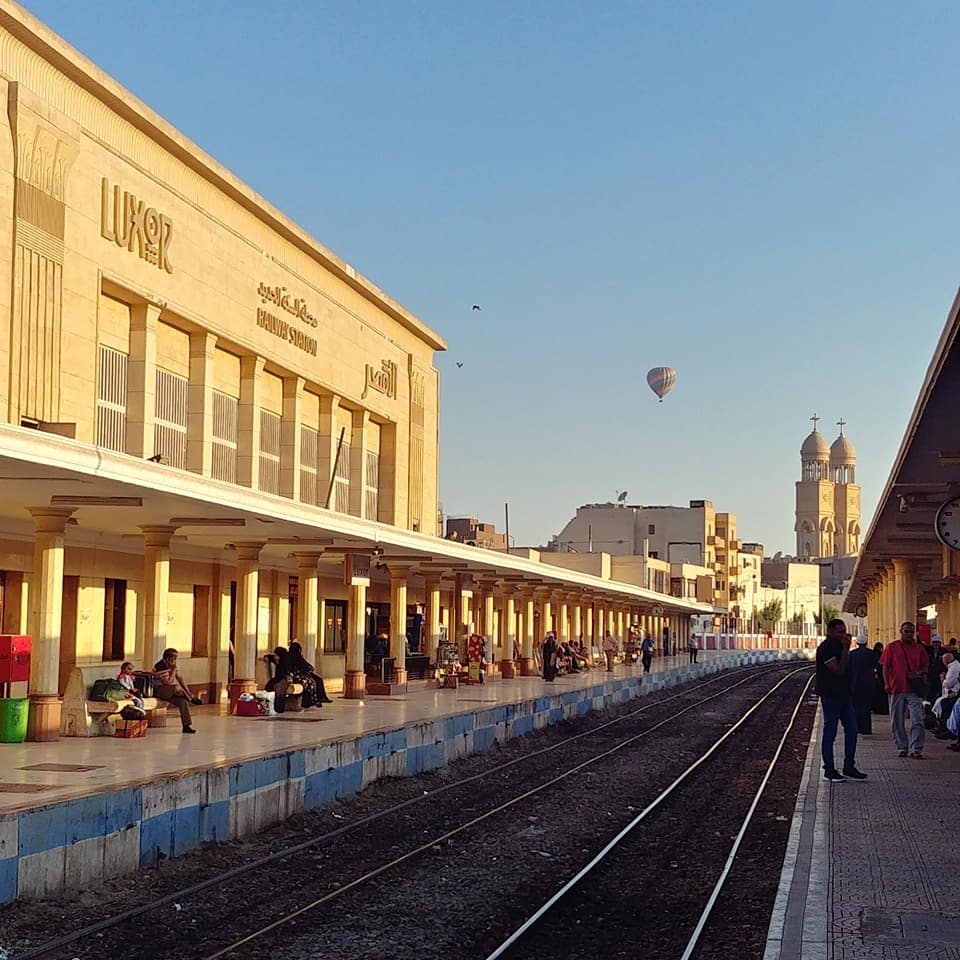 yellow railway station in Aswan at sunrise with hot air balloon in the background