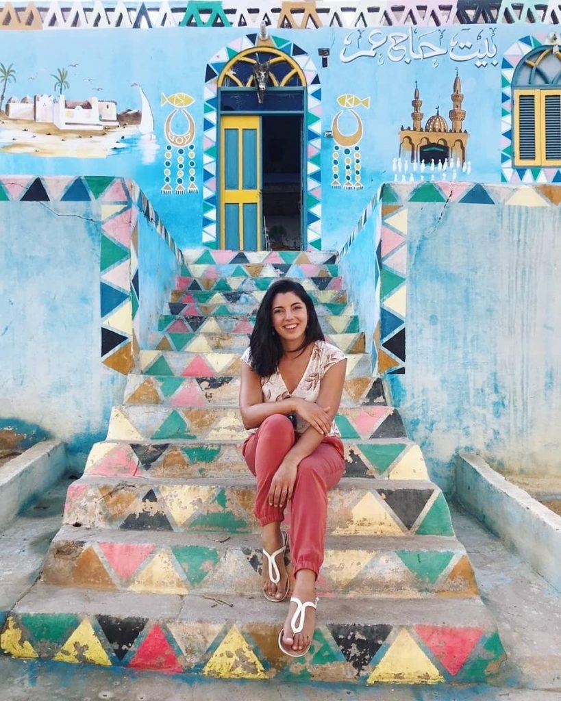 a girl sit on the stairs of a colorful house in the Nubian Village - Aswan