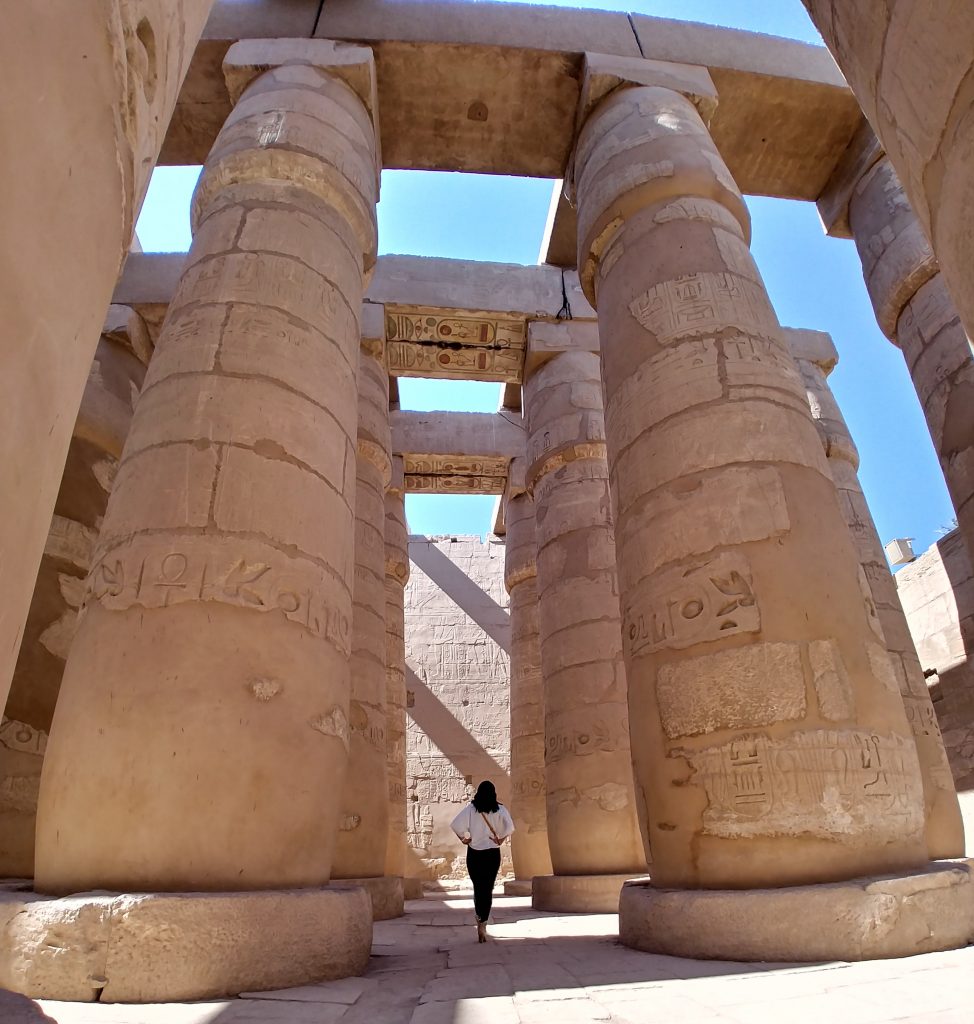 a girl walking in the middle of Karnak Temple - Luxor