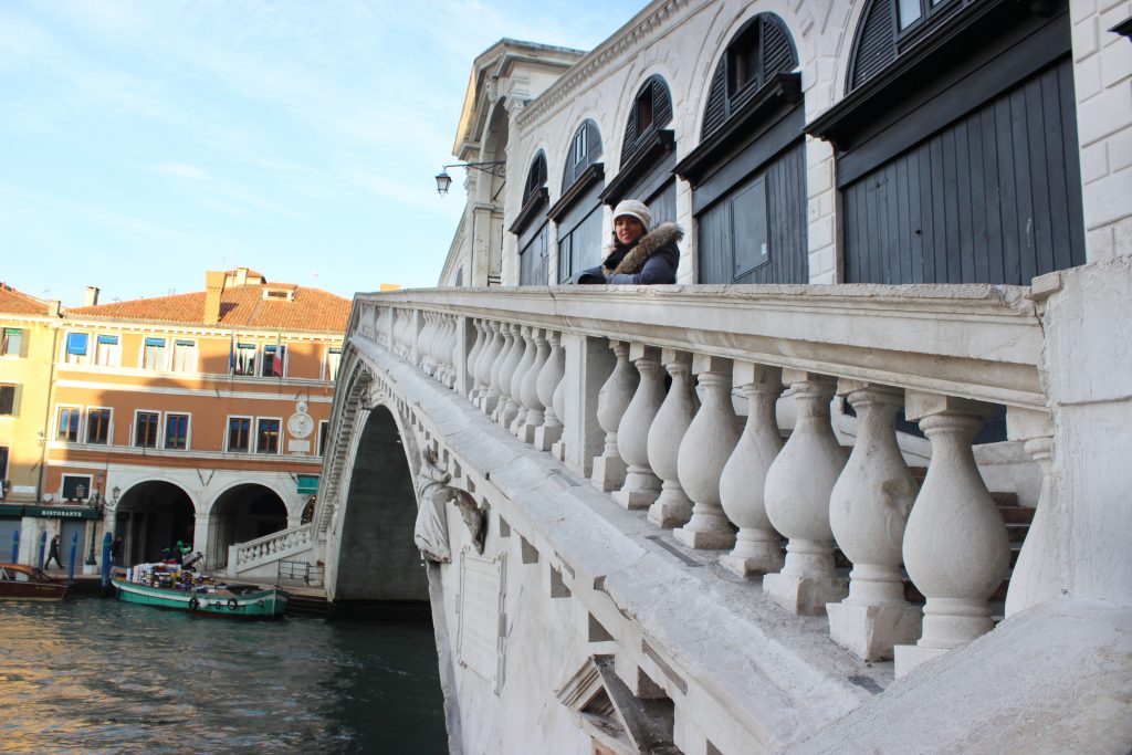a girl is standing in the middle of Rialto bridge in Venice