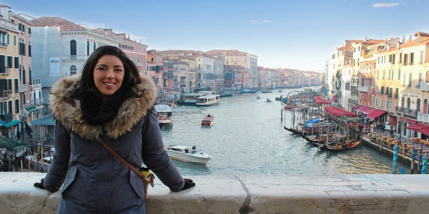 a girl is sitting on the Rialto bridge with view of the grand Canal in Venice