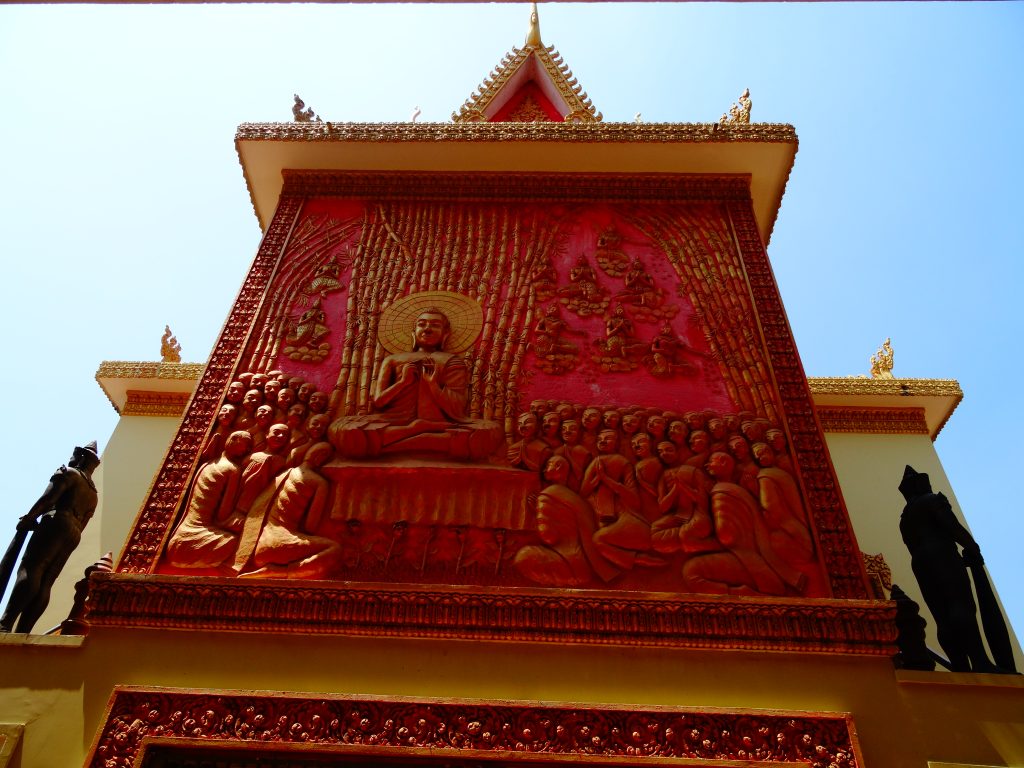 red sculpture of the buddha surrounded by monks at the Wat Ounalom