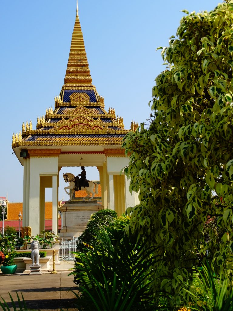 a golden stupa shelters the statue of ancient kign riddign a horse inside the royal palace
